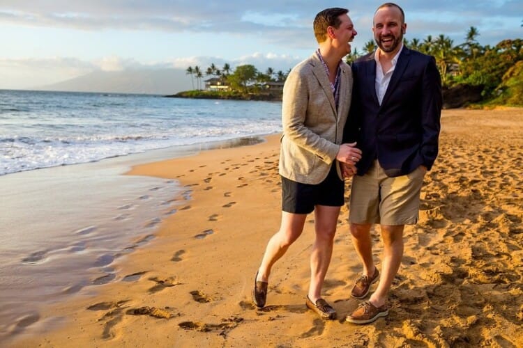 Engaged on Maui proposal planners: image of two men in shorts and blazers on the beach who are newly engaged and smiling at the camera